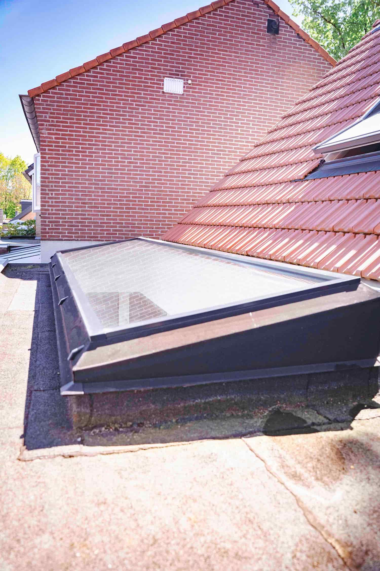 Luxlight lichtstraat op een plat dak naast het schuine pannendak van de woning