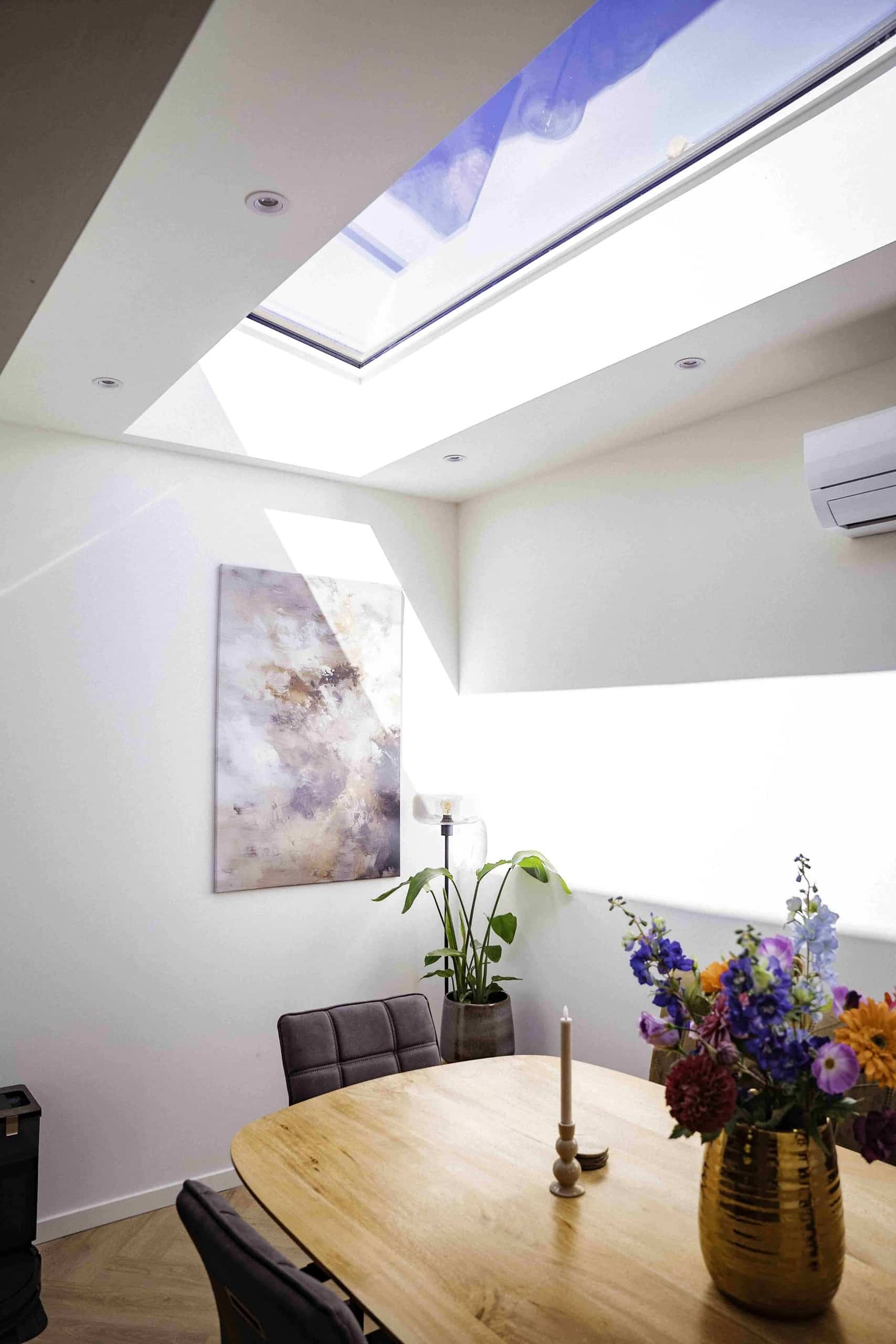 Lichtstraat boven de eethoek in een woonkamer in Bergen op Zoom met bloemen op tafel